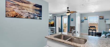 A kitchen with a granite countertop, a double sink, and a ceiling fan.