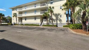 A multi-story hotel with balconies, a parking lot, and palm trees. - Sunset Suite (Navarre)