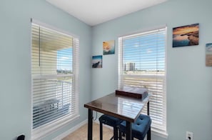 A room with two large windows, a table, and a chair.