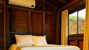 Une pièce de style cabane en bois, avec un lit, un banc et une fenêtre avec des rideaux.