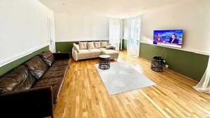 Een woonkamer met een bank, een salontafel en een aan de muur bevestigde televisie.