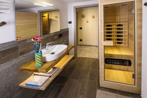 Une salle de bain moderne avec un meuble-lavabo en bois, un grand miroir et un sauna.