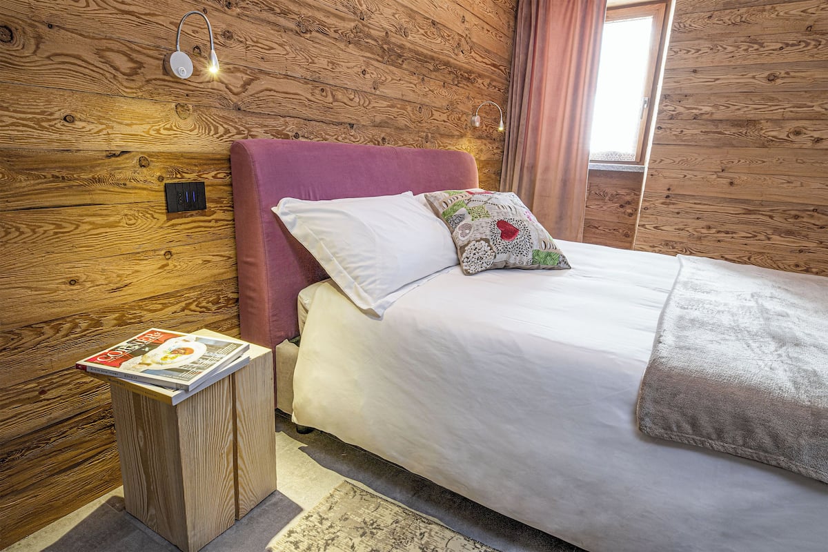 A wooden-paneled room with a bed, a nightstand, and a magazine.