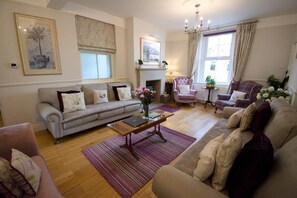 Un salon comprenant un canapé, des fauteuils, une table basse et une cheminée.