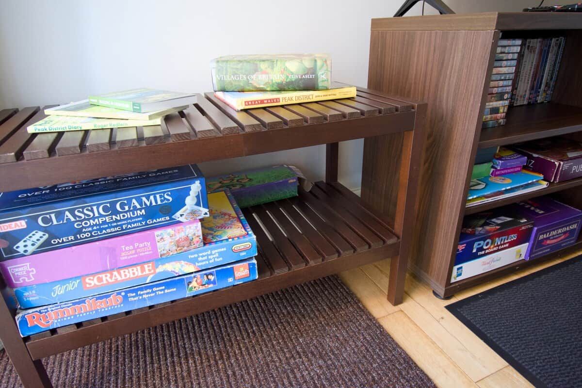 Una estantería de madera con libros y juegos de mesa.