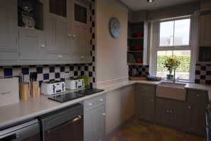 A kitchen with white cabinets, a clock, a window with a view, and a toaster on the counter.