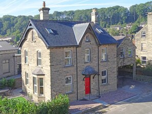 Un bâtiment en pierre avec une porte rouge, de nombreuses fenêtres et un toit en pente.