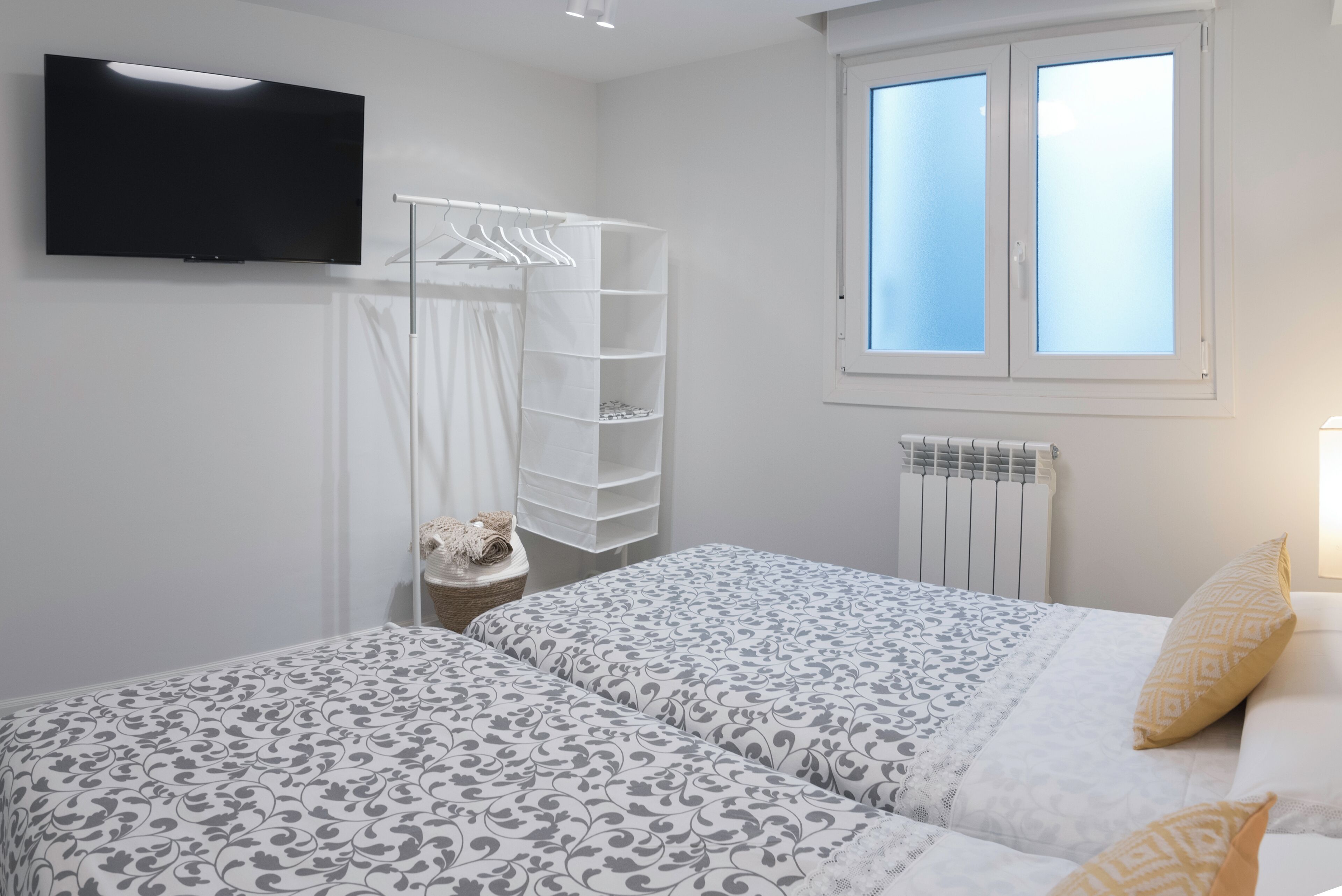 Un dormitorio con dos camas, televisión, ventana y radiador.
