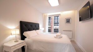 Une chambre avec un grand lit, une table de chevet avec une lampe, un radiateur et un téléviseur fixé au mur.