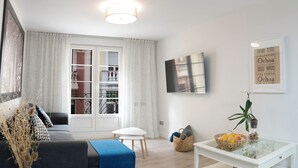 Un salon moderne avec un canapé, une table basse et un téléviseur fixé au mur.