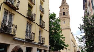 A street with buildings, a tower, and people walking.