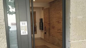 Une entrée avec une porte en verre, un sol à motifs et un mur en briques.