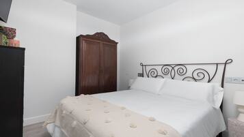 Een slaapkamer met een bed, een houten garderobe en een nachtkastje met een lamp.