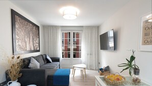 Un salon moderne avec un canapé, une table basse, un téléviseur et une fenêtre avec des rideaux.