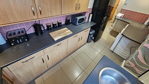 Une cuisine de taille réduite, dotée de meubles en bois, d’un four à micro-ondes, d’un grille-pain et d’un évier.