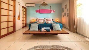 A room with a bed centered on a platform, a surfboard on the wall, and a traditional Japanese sliding door. - Bounty Lodge - Private spa and view (Punaauia)