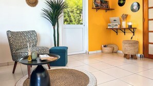 A living room with a patterned armchair, a blue sofa, a round table, and a large plant. - Bounty Lodge - Private spa and view (Punaauia)