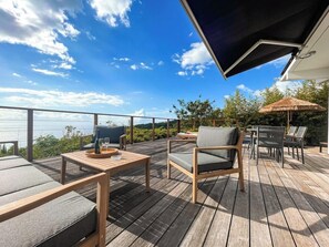 A wooden deck with outdoor furniture, including a table and chairs, overlooking a scenic view.