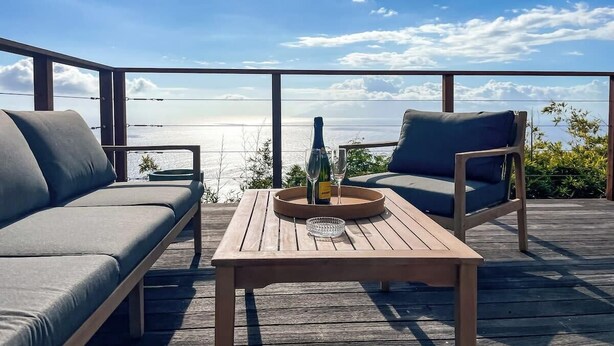 A wooden deck with a sofa and two chairs, a bottle of champagne, and two glasses on a tray. - Bounty Lodge - Private spa and view (Punaauia)