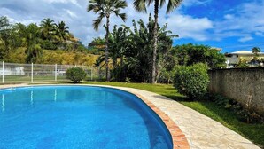 Ein Pool mit geschwungener Kante, umgeben von einer Steindeck und einem weißen Zaun.