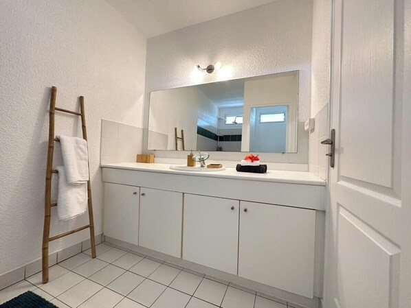 Une salle de bain avec un meuble-lavabo blanc, un grand miroir et une échelle en bois.