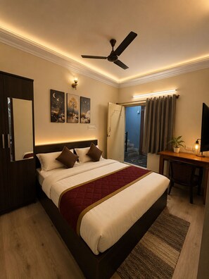 Ein Hotelzimmer mit Bett, Schreibtisch, Stuhl, Deckenventilator und Blick ins Freie.