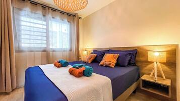 A bedroom with a bed, a bedside lamp, and a window with curtains.