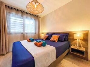 Quarto com cama, luminária de cabeceira e janela com cortinas.