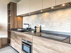 A modern kitchen with wooden cabinetry, a black countertop, and built-in appliances.
