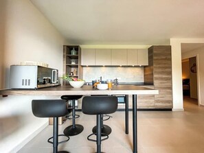 Cozinha moderna com ilha central, banquetas e micro-ondas.