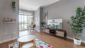 Ein modernes Wohnzimmer mit Essbereich, einem Flachbildfernseher und einem Blumentopf.