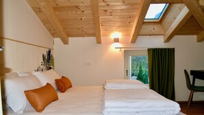 A bedroom with a skylight, a bed with white and orange bedding, a green curtain, and a chair. - Nine Rooms Shared (Trento)