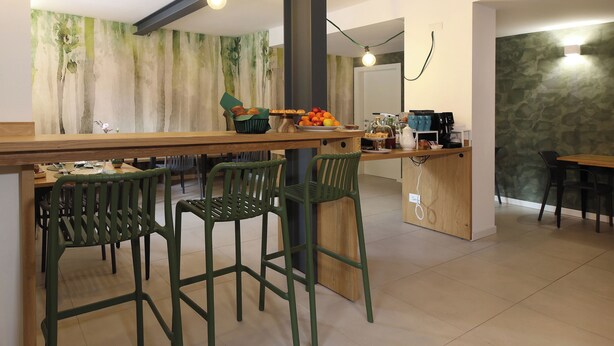 A modern kitchen with a central island, bar stools, and a stone accent wall. - Nine Rooms Shared (Trento)