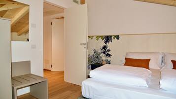 A bedroom with a bed, a bedside table, and a door leading to another room.
