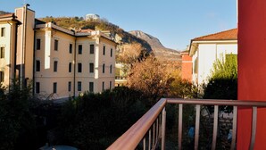 A residential area with buildings, a mountain in the background, and a car parked in front. - Nine Rooms Shared (Trento)