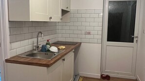 Una cocina compacta con armarios blancos, encimera de madera y salpicadero de azulejos.