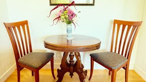 A dining table with two chairs, a vase with flowers, and a framed picture on the wall. - Raven's View - Walk to town, beach, restaurants (Inverness)