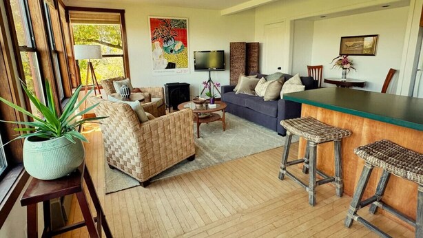 A spacious living area with a sofa, two armchairs, a coffee table, and a bar area with stools. - Raven's View - Walk to town, beach, restaurants (Inverness)