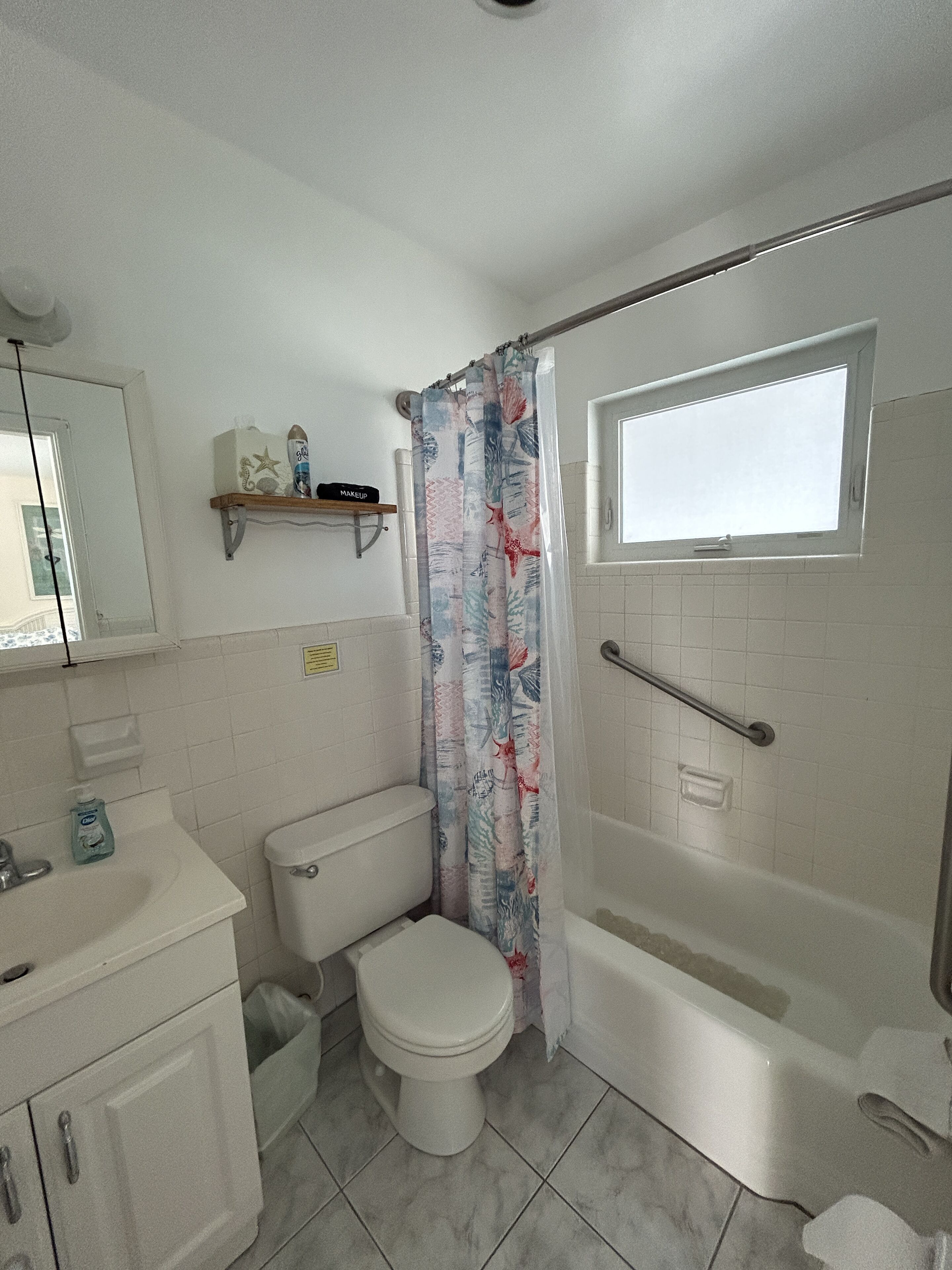 A bathroom with a toilet, sink, and bathtub. There is a shower curtain with a floral pattern.