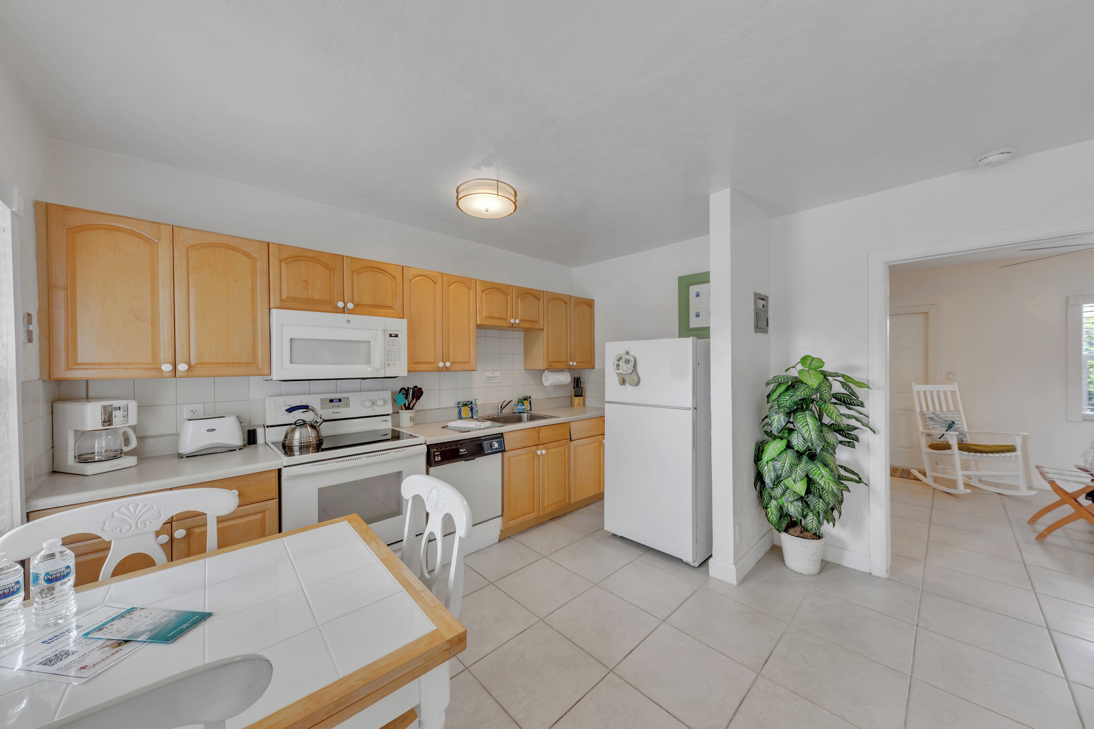 A modern kitchen with wooden cabinets, white appliances, and a dining area with a table and chairs.