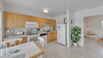A modern kitchen with wooden cabinets, white appliances, and a dining area with a table and chairs.