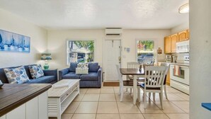 A compact living space with a sofa, dining table, chairs, and a kitchenette. - Bahama Beach Club Pompano (Pompano Beach)