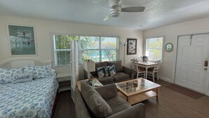 A well-lit room with a bed, two sofas, a dining table, and a ceiling fan. - Bahama Beach Club Pompano (Pompano Beach)