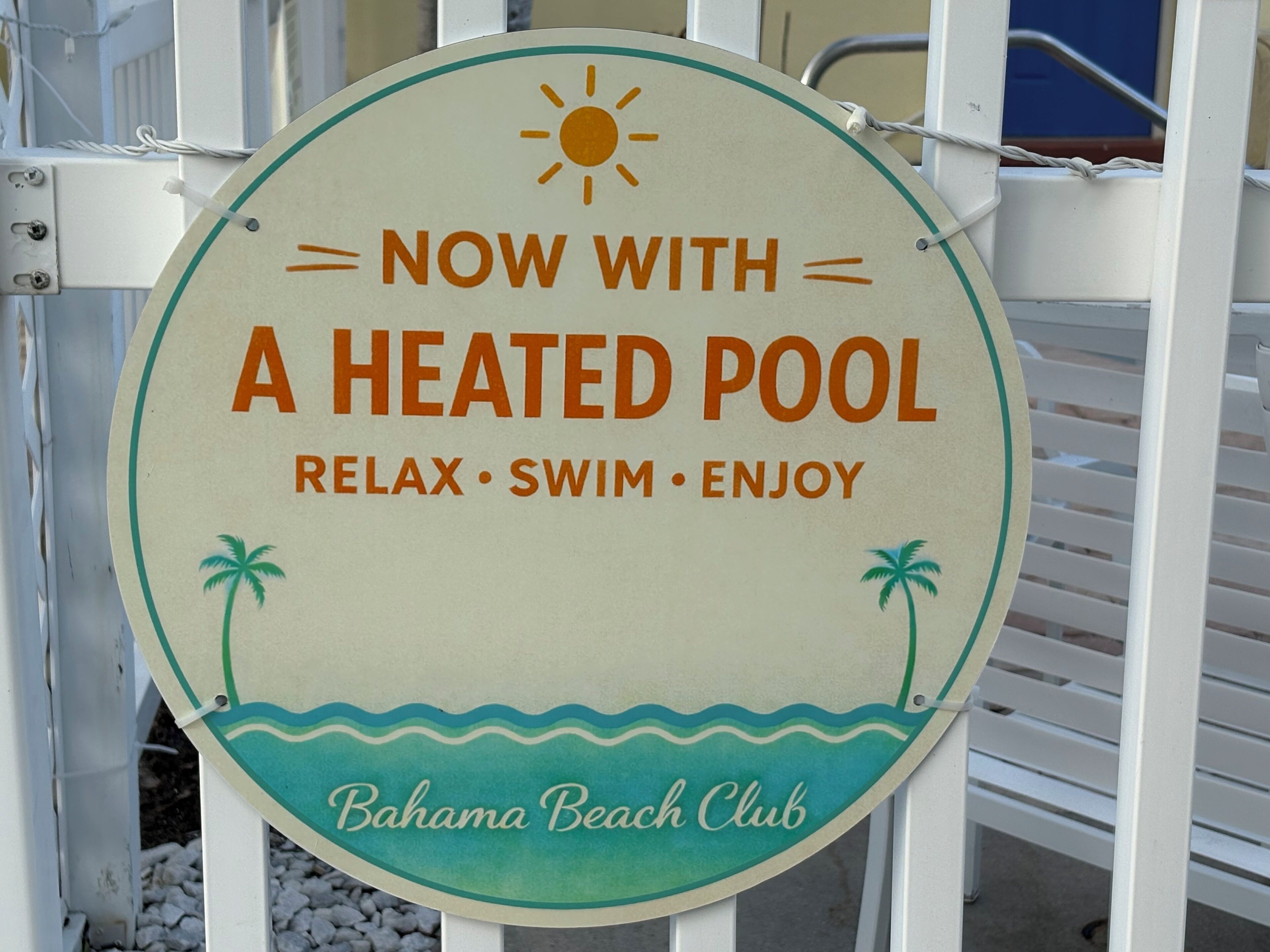 En rund skylt med en sol, palmer och vågor, som annonserar för en uppvärmd pool på Bahamas Beach Club.