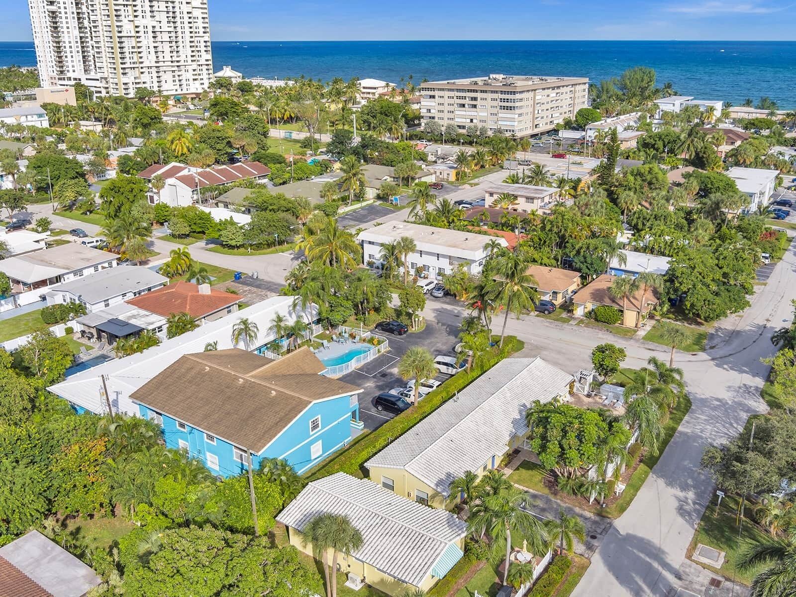 Vue aérienne d’un quartier résidentiel situé sur la côte, où se côtoient des maisons unifamiliales et un grand bâtiment d’hôtel.