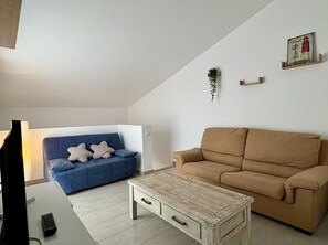 A living room with a blue sofa, a brown sofa, a wooden coffee table, and a wall-mounted plant.