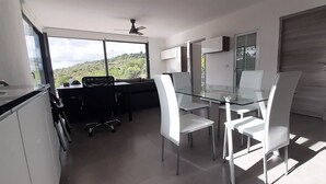 Eine moderne Küche mit Essbereich, großen Fenstern und Blick ins Freie.