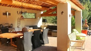 An outdoor patio with a wooden table and chairs, a sofa, and a bench. - La Caracole :Provencal villa with heated pool, tennis court, nature at your doorstep (Caseneuve)