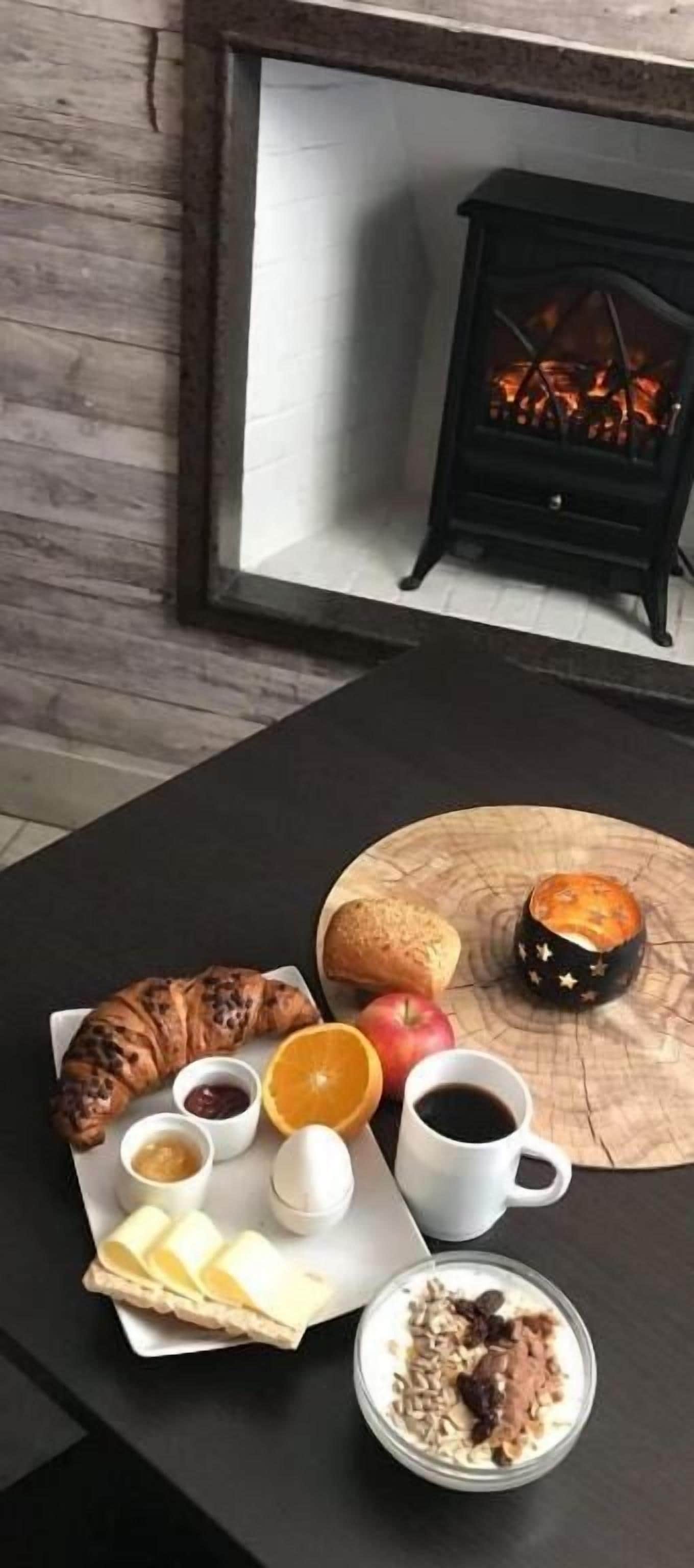 Aamiaispöytä, jossa on croissantteja, leipää, hedelmiä, kahvia ja muffinssi.