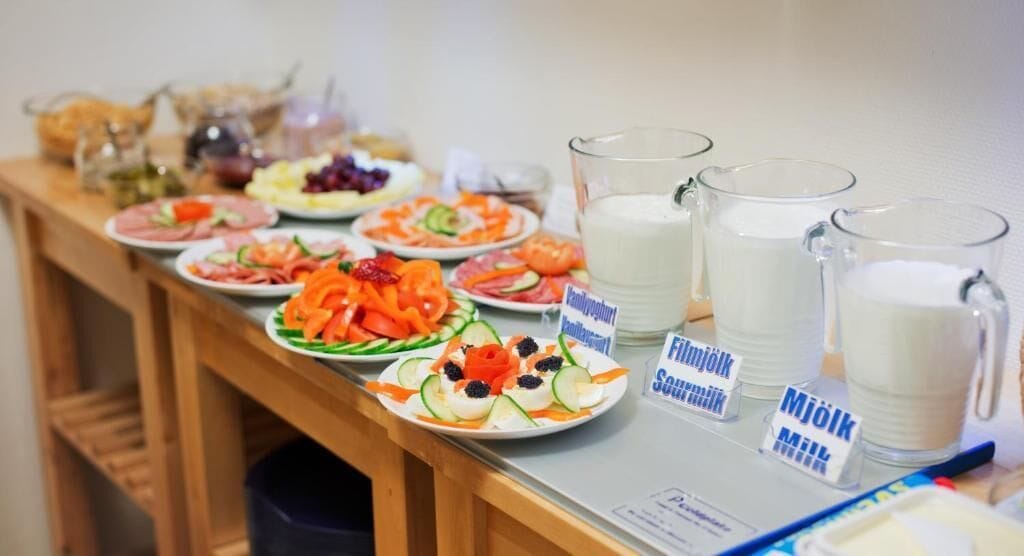 Una mesa de buffet con diversos alimentos y jarras de leche.
